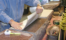 Closeup of a worker applying a stencil to a stone.